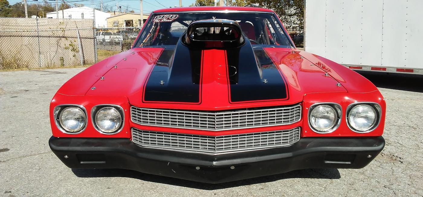 The Chevelle head on, twin black hood stripes over red, cowl scoop and quad headlights