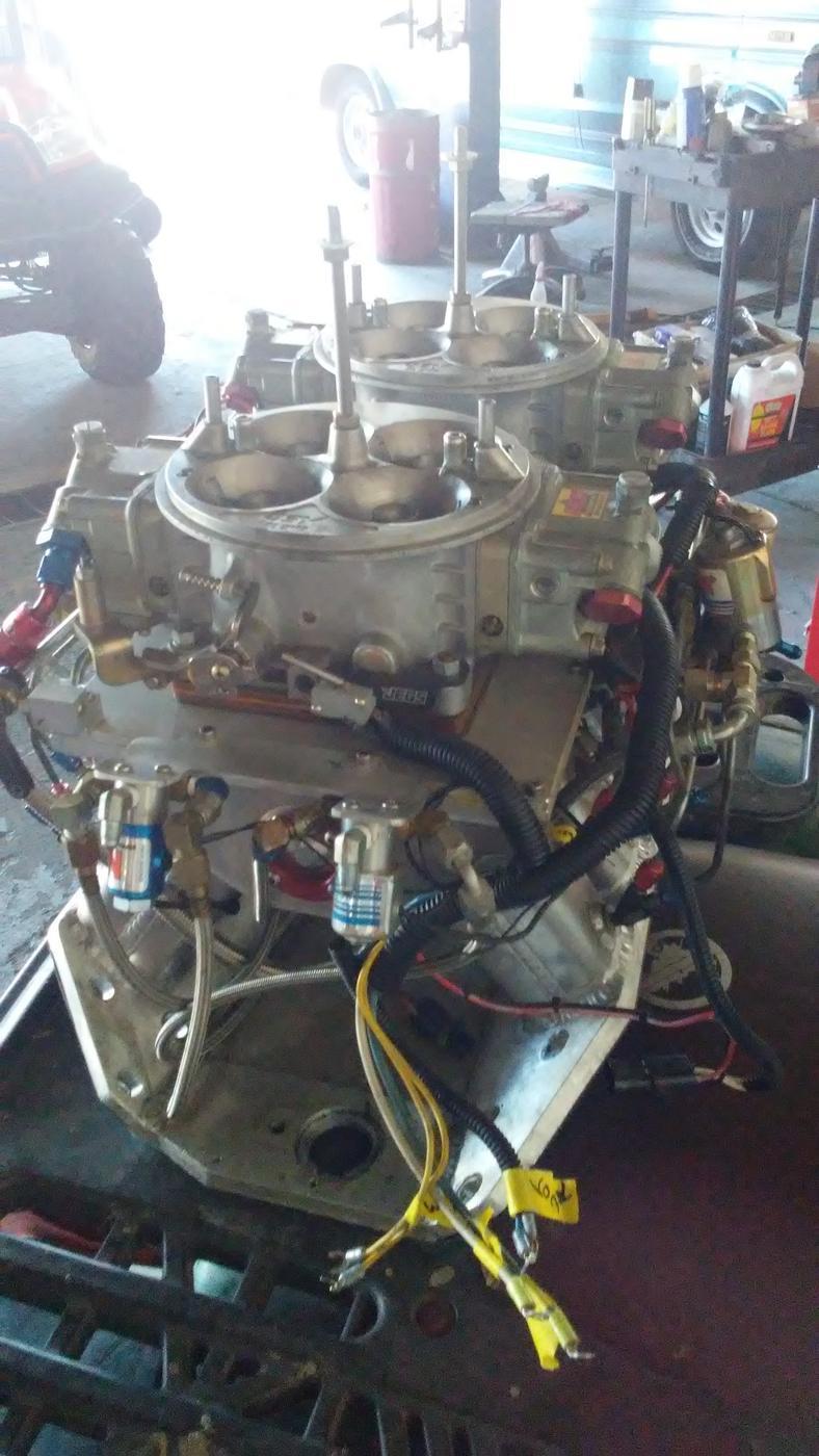 The tunnel ram assembly stood up in the shop, wiring loom draped over the intake
