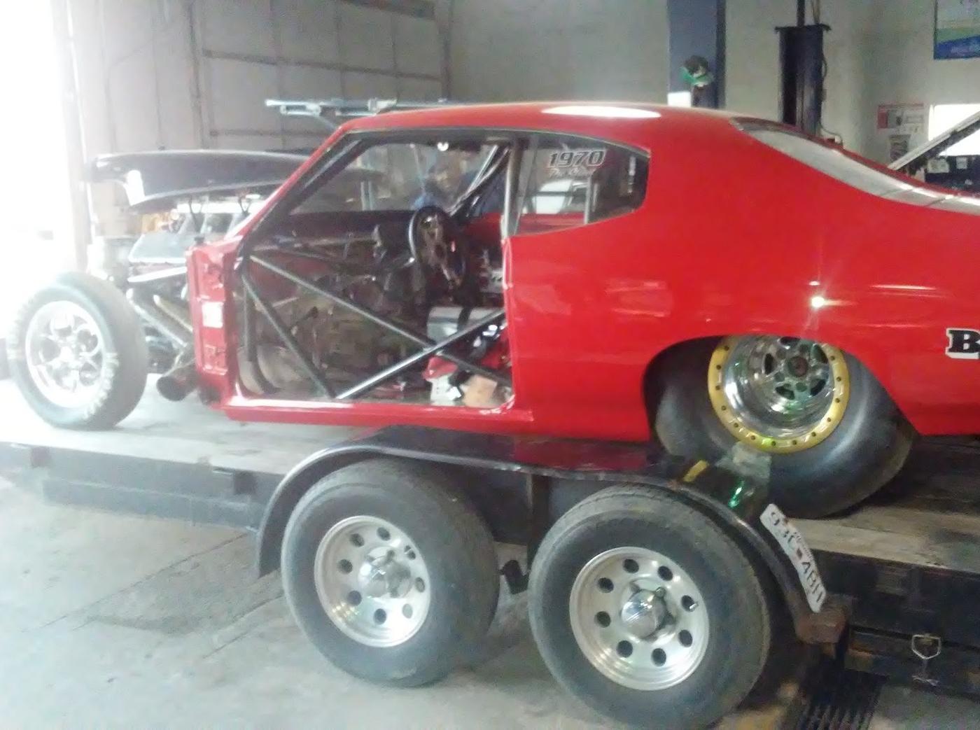 The red Chevelle on its trailer inside the Big E's workshop, next to the lift and the parts bench